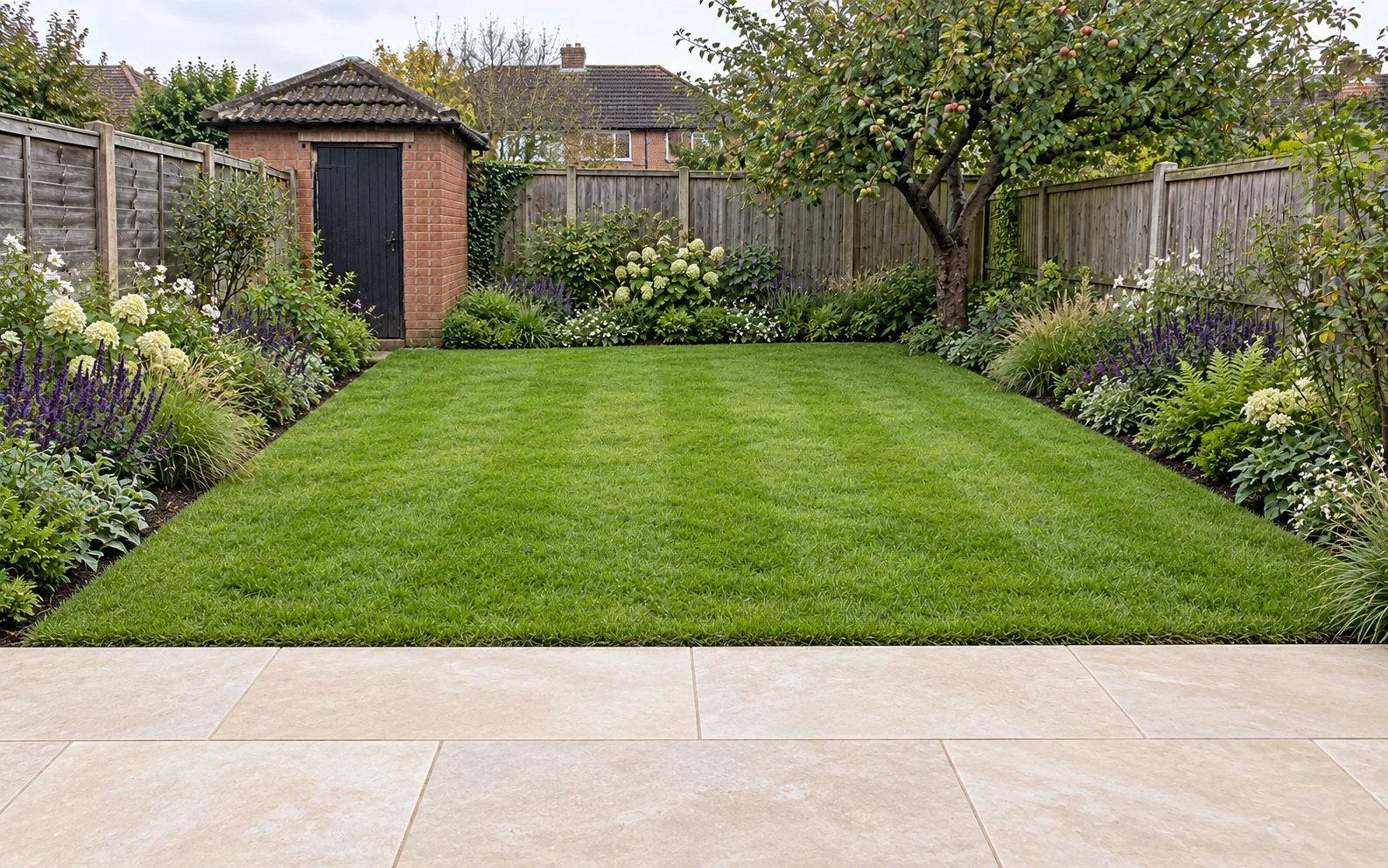 A new stone patio with lawn and planted borders