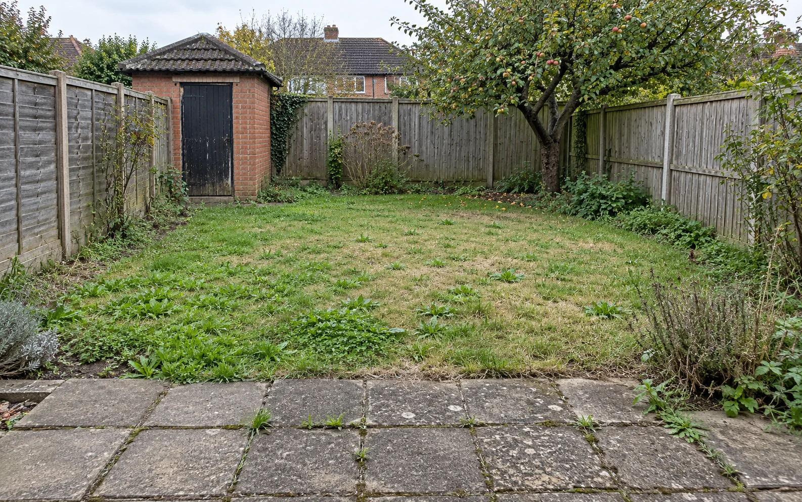 Illustrative garden before landscaping, with worn paving and patchy lawn